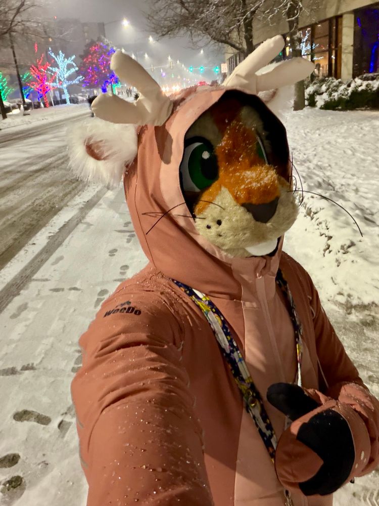 Squirrel fursuiter dressed in a pink deer snowsuit 