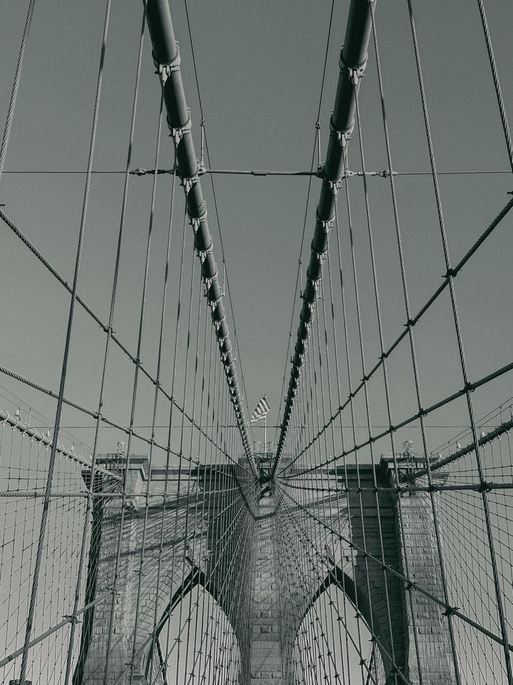 One of the towers of the Brooklyn bridge with cables and stays attached and covering both sides of the image 