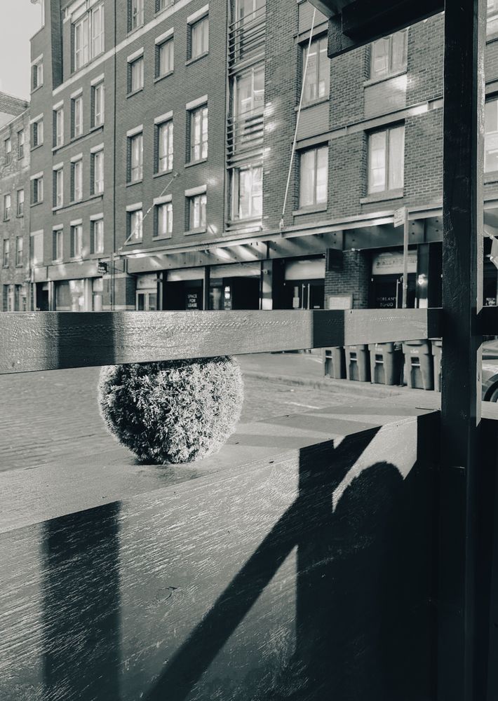  Shadows and sunlight on a wooden outside restaurant seating area on a city street 