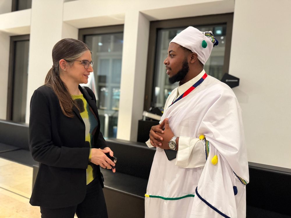 A woman and a man in conversation, the man wearing a traditional white garment. 