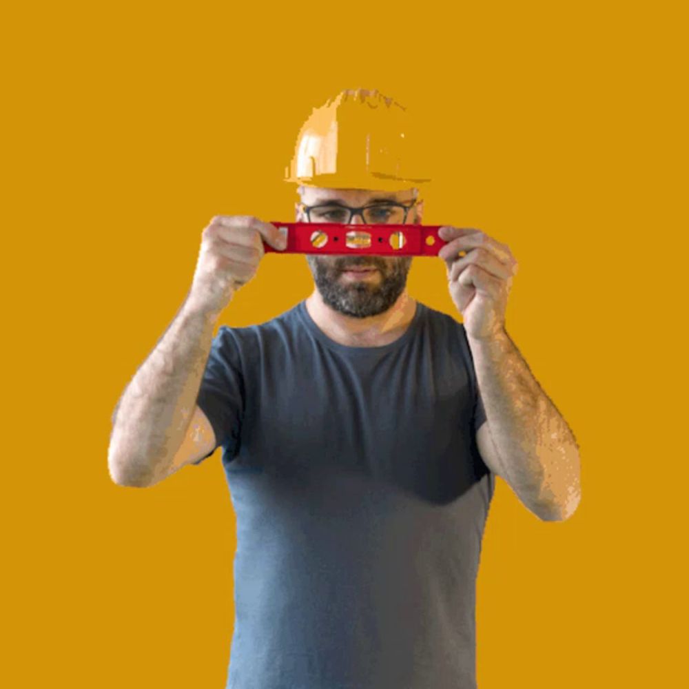 a man in a hard hat is holding a red level in front of his face