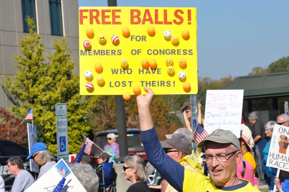 Person holding sign at No Kings rally. Yellow sign with different ping pong balls glued to it that reads: Free Balls! For members of Congress who have lost theirs!