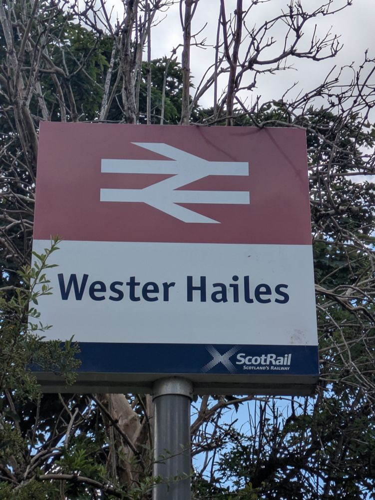 A station totem sign stating "Wester Hailes" underneath a double arrow symbol