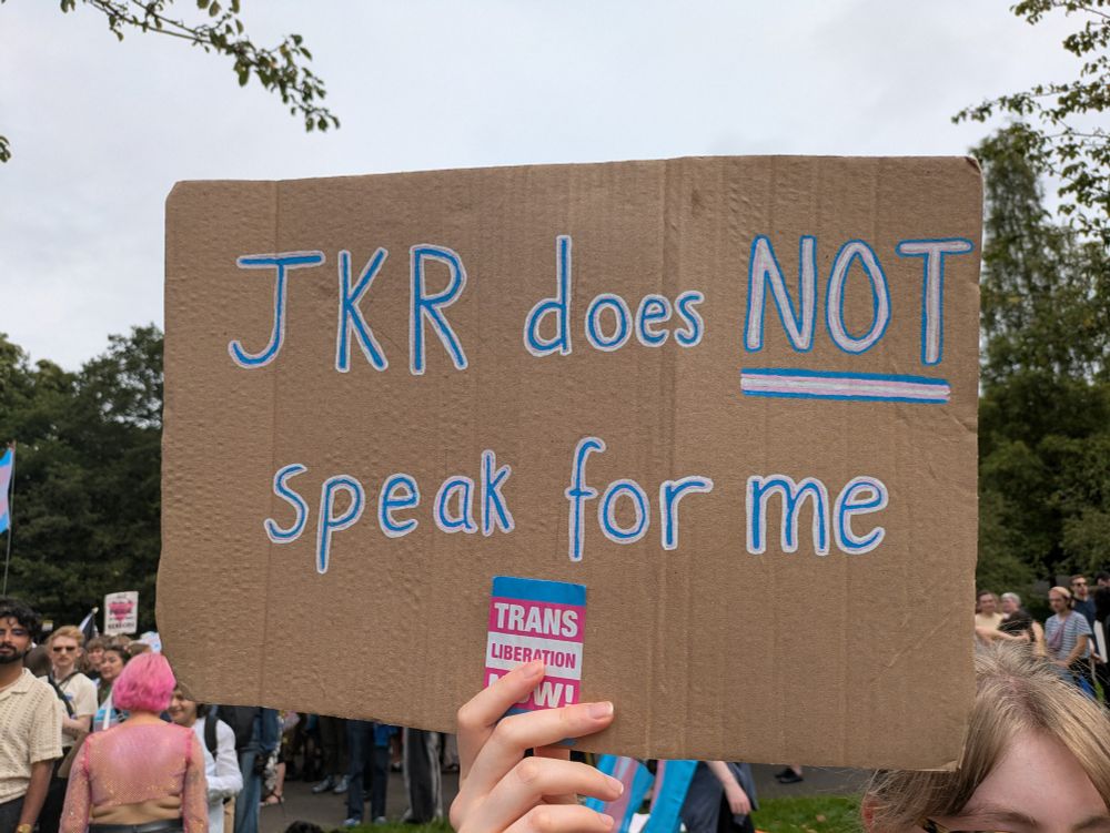A cardboard sign which reads in blue, pink and white text "JKR does NOT speak for me"