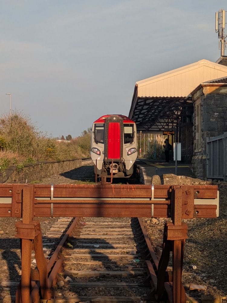 The front of a Class 197 train about 25 meters in the background to a pair of buffer stops at Pembroke Dock station 