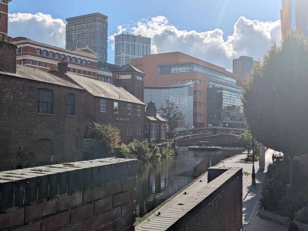 A view of a canal and a mix of old and new buildings around it in the sun