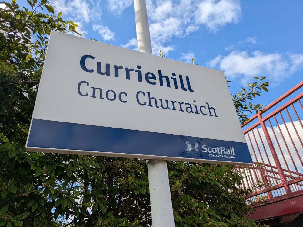 A station sign which reads...
Top Line: Curriehill 
Bottom Line: Cnoc Churraich