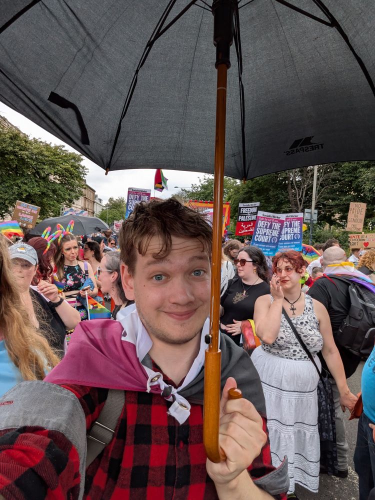 Me, a white man in a red and black checked flannel holding an umbrella 