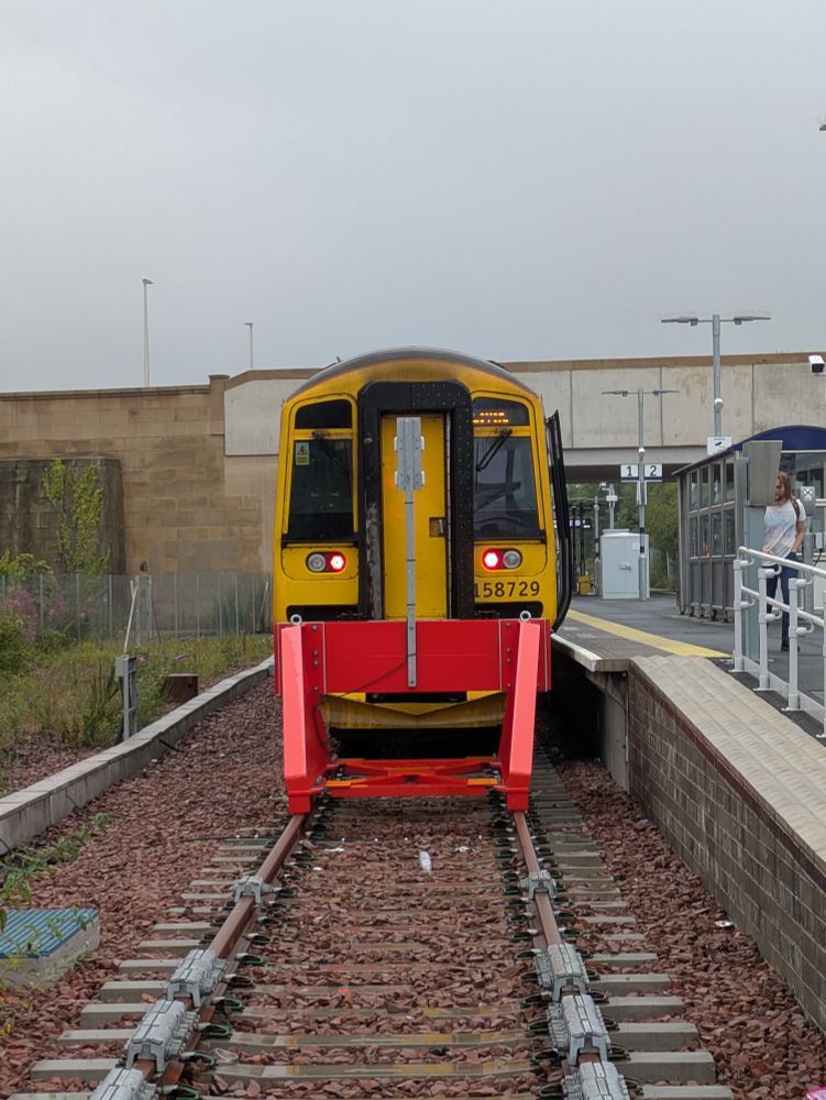 A Class 158 train at Leven train station behind a pair of red buffers