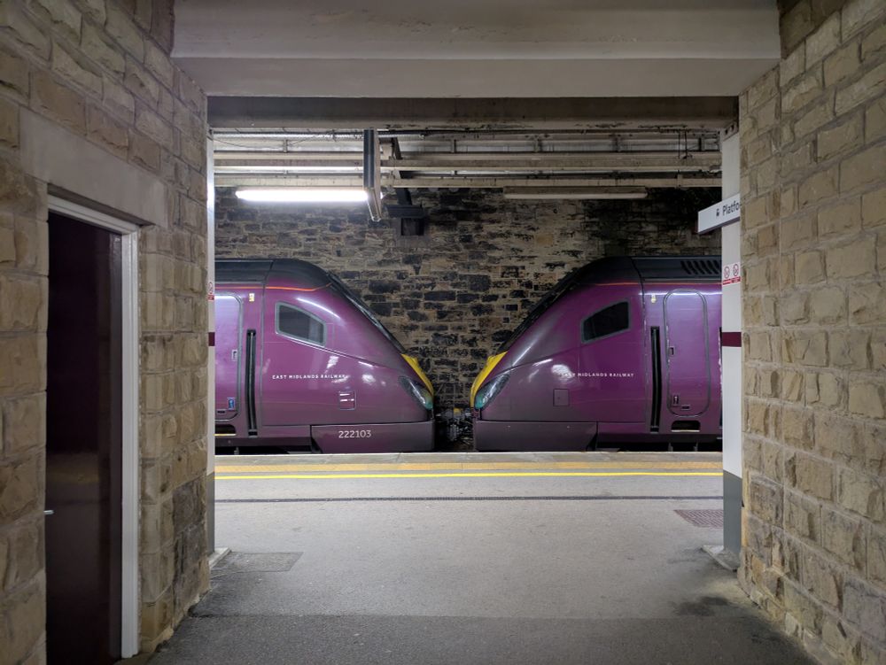 A pair of Class 222 Meridians seen side on. The photo is framed with buildings surrounding the train 