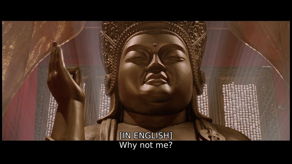 A big ole Buddha, looking chill, as John yells "Why not me?" at it/