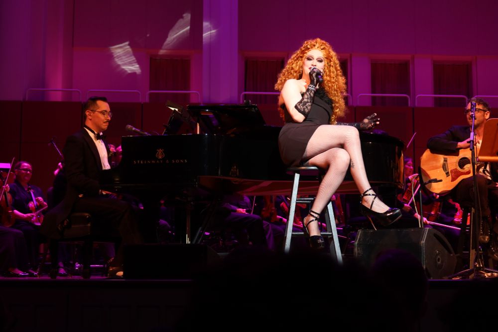 Jinkx with her band, sitting by the piano singing