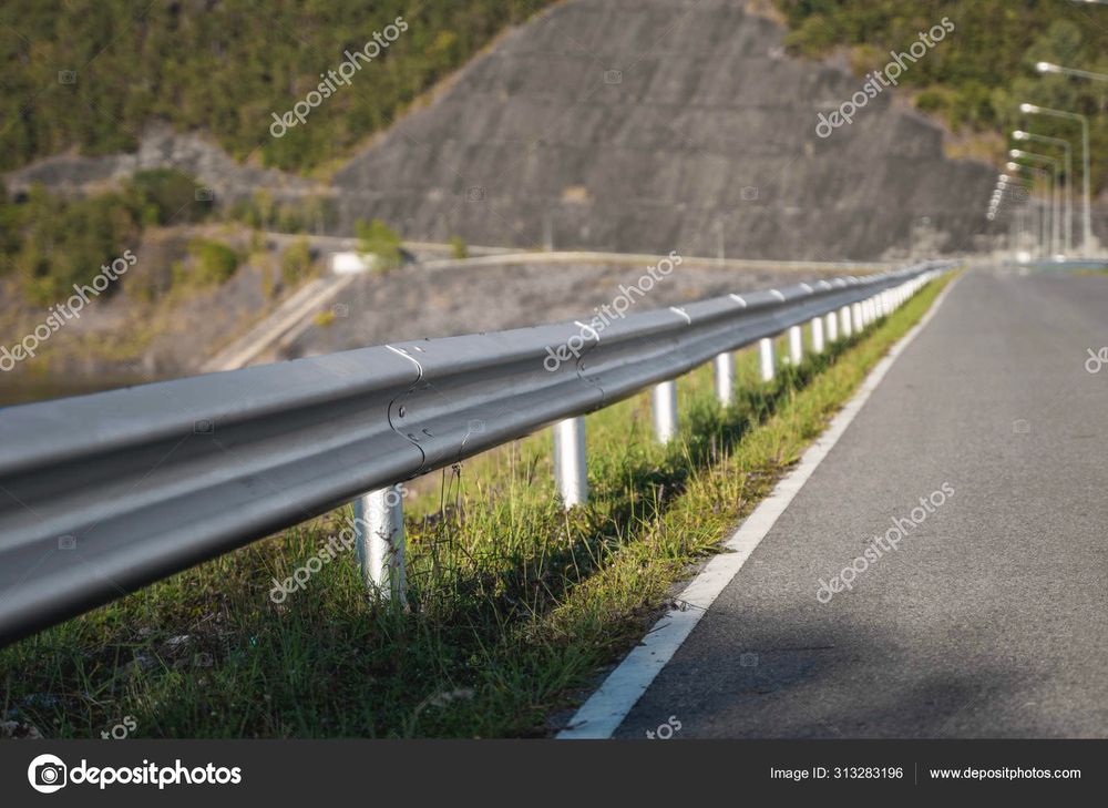 Pont d’autoroute avec une barrière et de l’herbe de l’autre côté. 