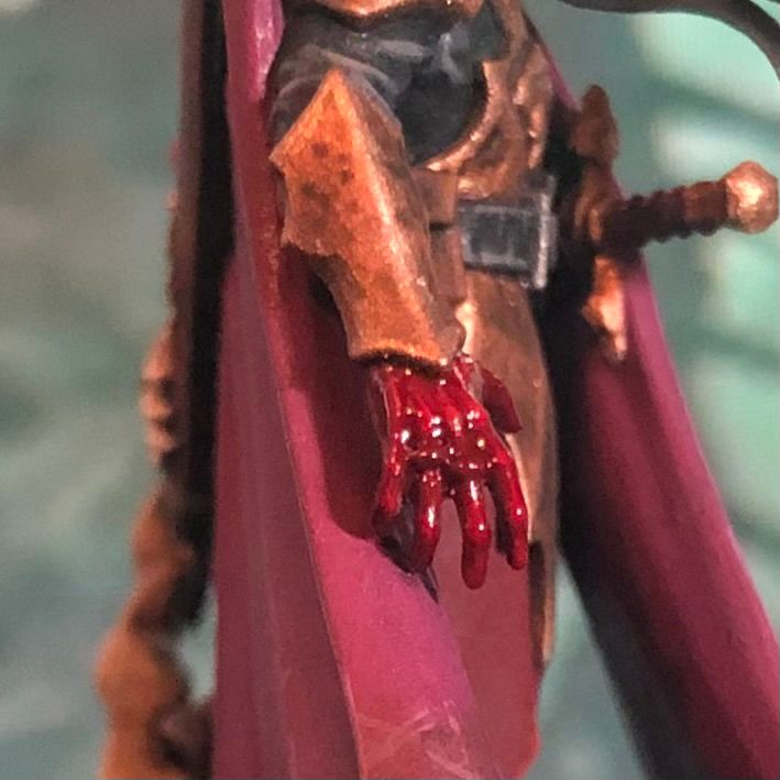 A painted miniature close up of a bloody hand.