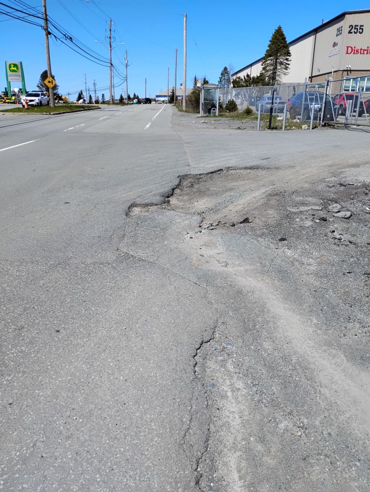 An uneven road surface leads to the bus stop opposite Access NS. There is nowhere for people who wheel to go except in the road. 