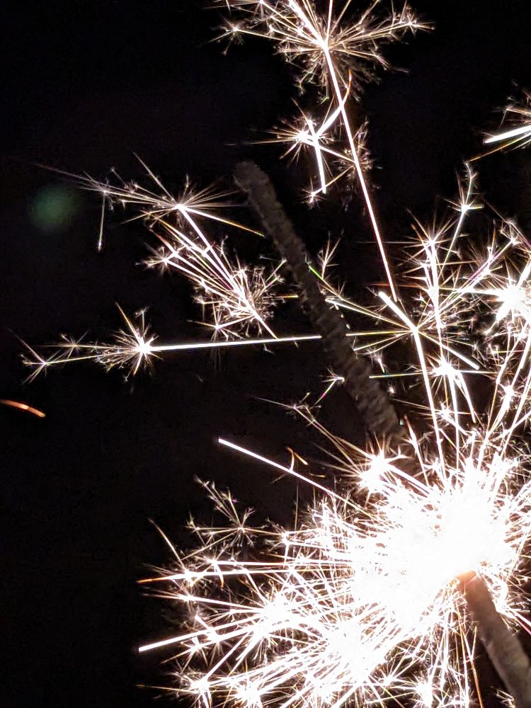 Close-up photo of a fizzing sparkler against a black night sky