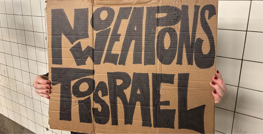 Cardboard protest sign that reads “No weapons to Israel”