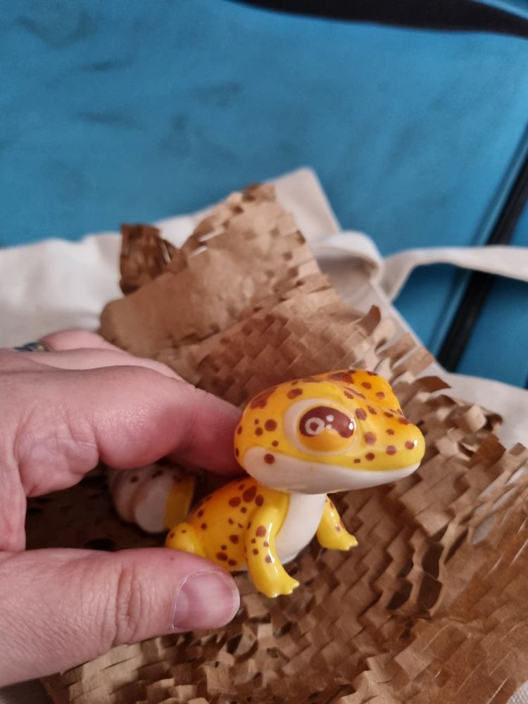 An absolutely adorable hand painted figure of a leopard gecko by Derptiles. He is being held carefully.
