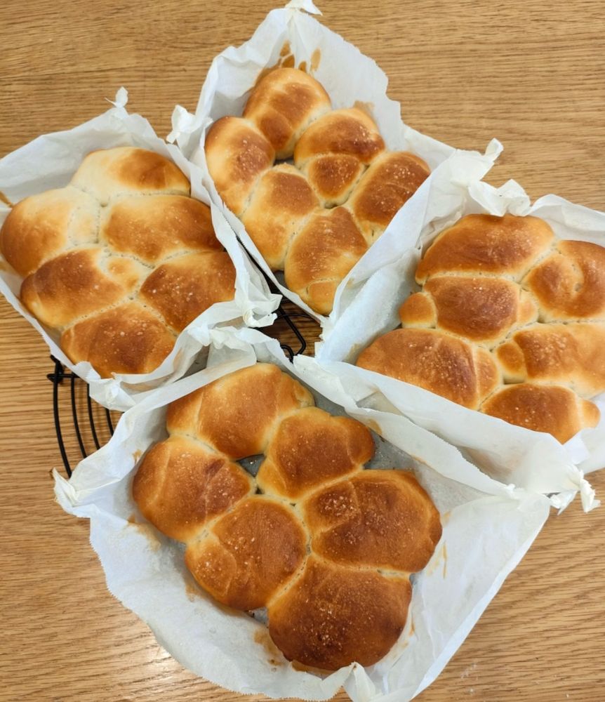 クッキングペーパーの四隅をひねった型に入った塩ちぎりパンが4つ、丸網の上に並べられている写真。1つのちぎりパンは6つのパンが繋がってできている。