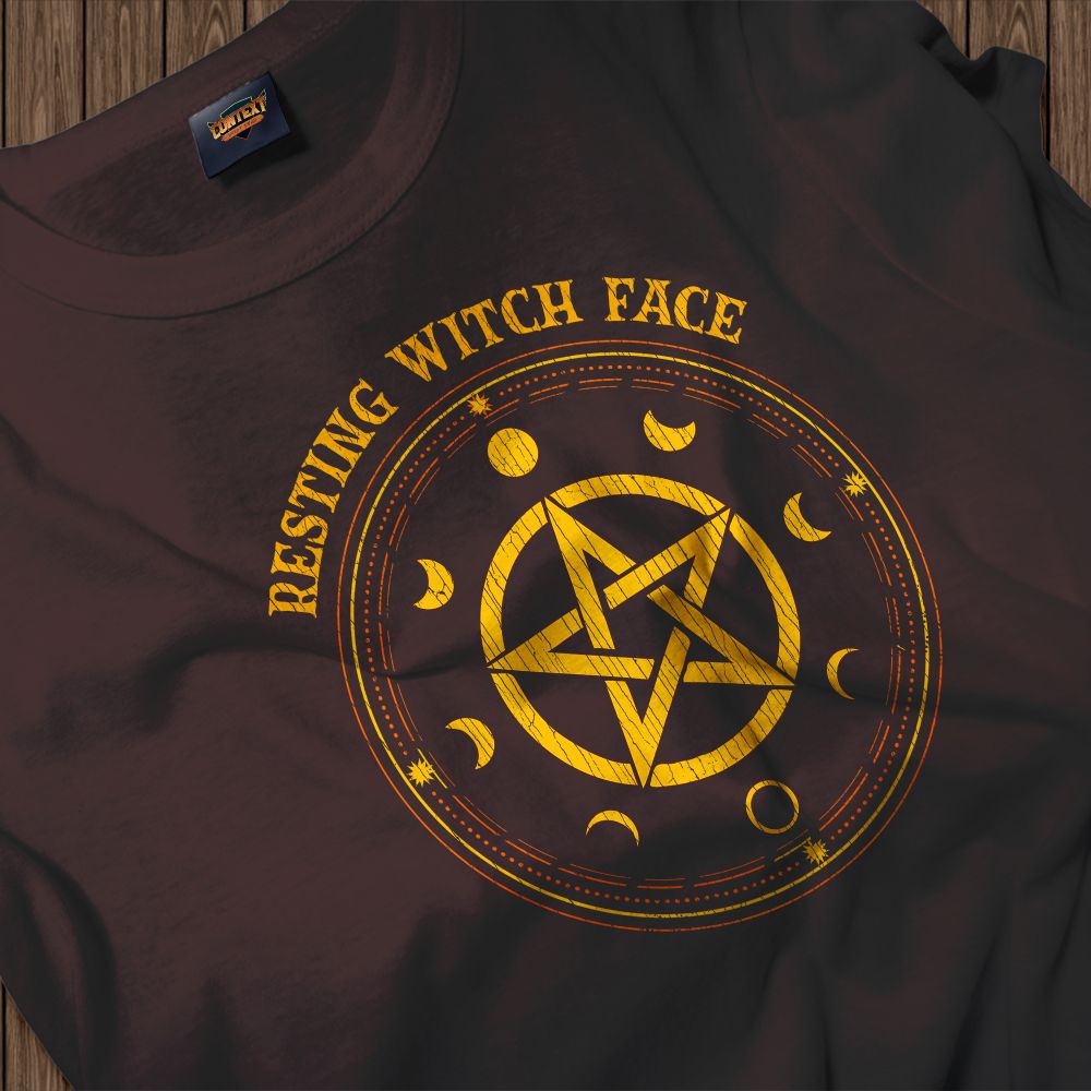 A dark chocolate brown t-shirt is displayed flat. It features a large, golden-yellow distressed pentagram design in the center, encircled by various phases of the moon. Above and below the symbols, the phrase "Resting Witch Face" is written in a matching vintage, weathered font. This design playfully combines modern slang with occult aesthetics. The use of moon phases and the pentagram represents the connection to lunar cycles and nature-based spirituality, making it a perfect piece for anyone who embraces their inner "kitchen witch" or mystical side.