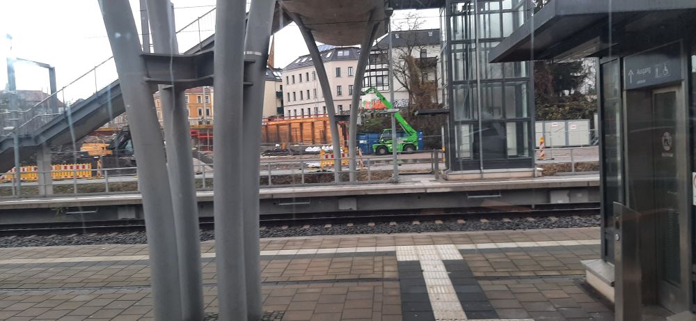 Blick vom S-Bahnhof Connewitz nach Osten, im Bild die Brückenpfeiler der bestehenden Fußgängerbrücke über die Bahnsteige, im Hintergrund die Baustelle der Brückenverlängerung.
Erkennbar sind eine Abstützung (Berliner Bau) und ein grüner Teleskoplader vor den Häusern an der Tram-Wendeschleife.