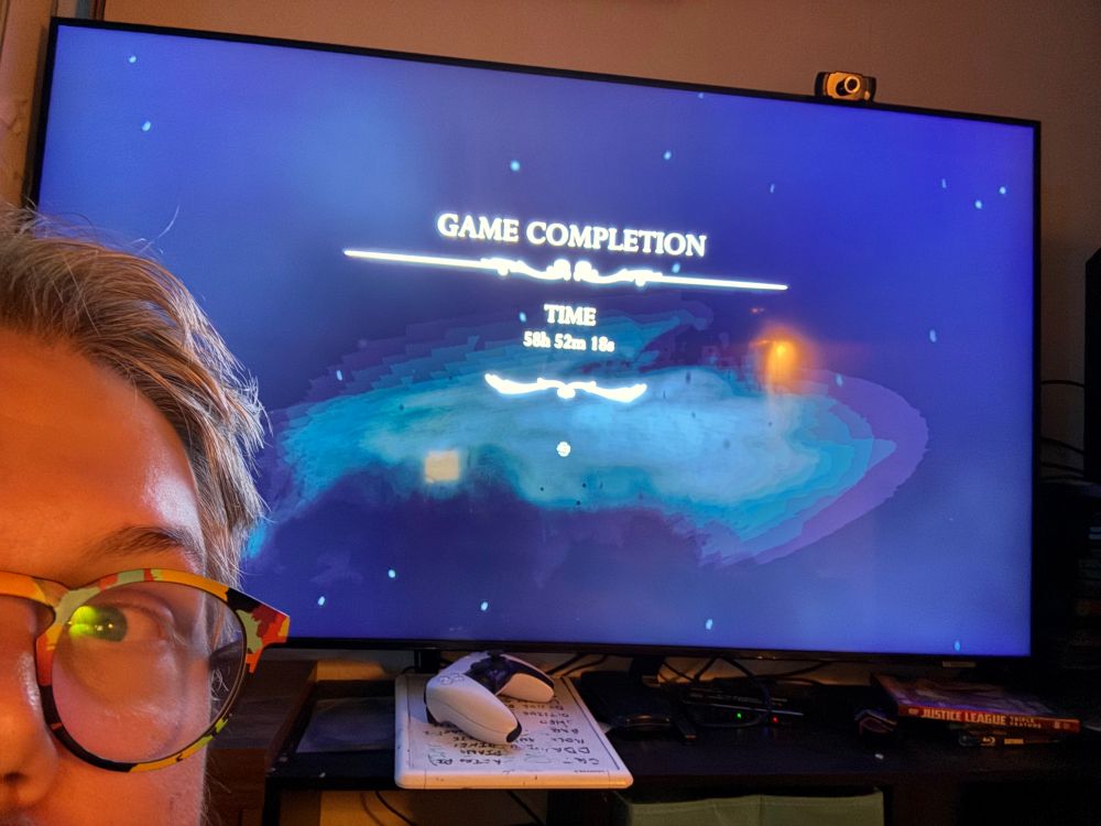 Me leaning into frame in front a tv showing a completion time of 58 hours and 53 minutes. 