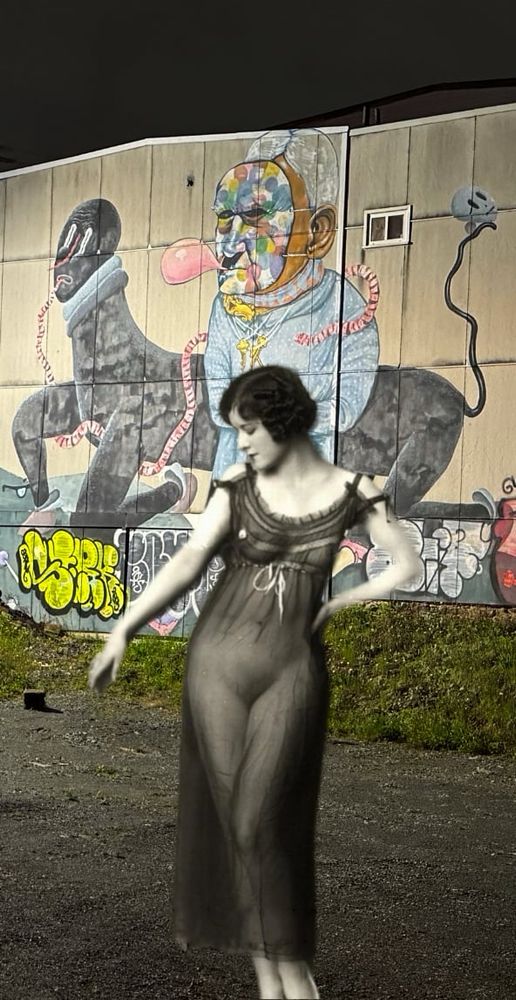 A scantily clad dark haired woman posing in front of a mural in north end Halifax
