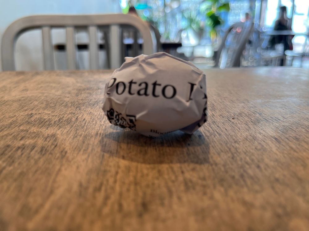 A small potato wrapped in paper on a cafe table