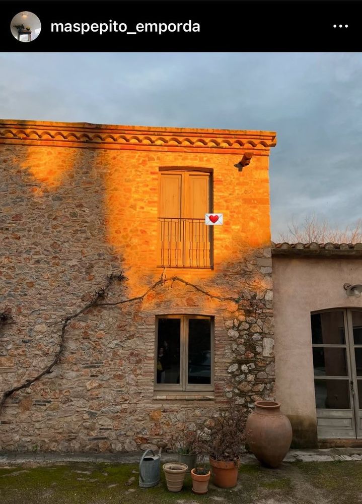 Exterior wall of a farmhouse built of red bricks. Two windows on top of each other, the top was shone by the sunlight