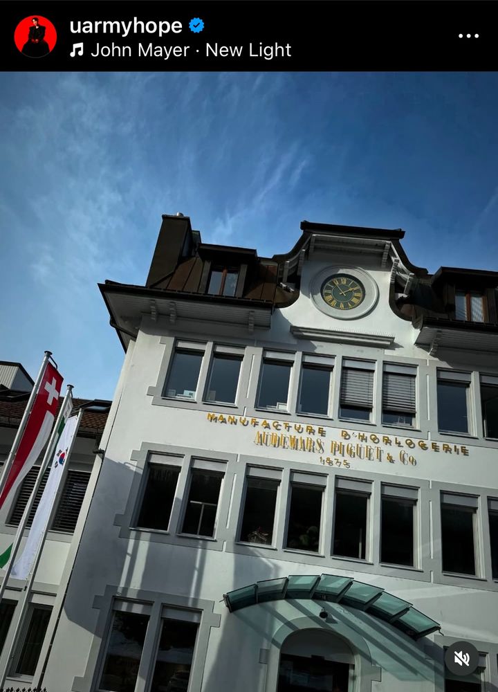 Entrance of the Audemars Piguet historical house at Le Brassus.

It’s a two-storey building with a clock on the top. The external wall is white. A row of windows with their blinds opened.
On the left side, were a line of the Swiss flag, Canton Vaud flag & South Korean flag. All are in vertical banner format.