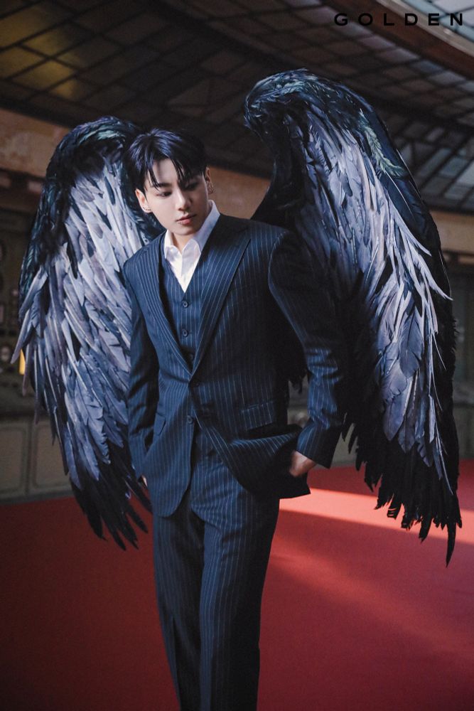 An Asian man [Jungkook of BTS] wearing black suit with feathery wings