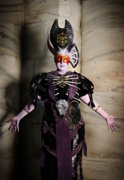 Amy as The Architect from Dragon Age, in cosplay. A lavender demonic costume with black and purple elements, with a tall black headpiece.