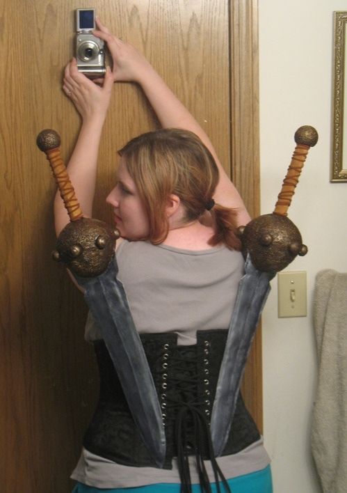 Amy displaying the swords that attach to her Isabela corset using magnets, photo in mirror from the back