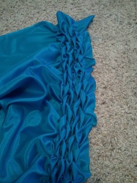 In-progress photo of a blue satin fabric being hand-smocked into a dragon scale pattern