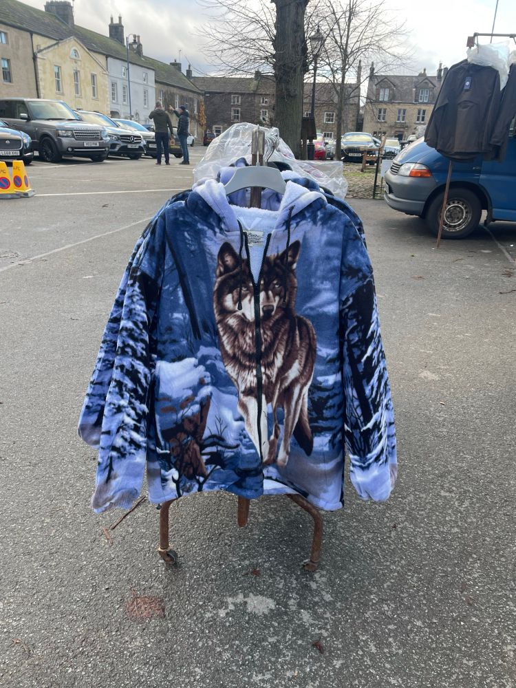 A rack of fleeces with illustrated wolves printed on them, for sale in Masham market.