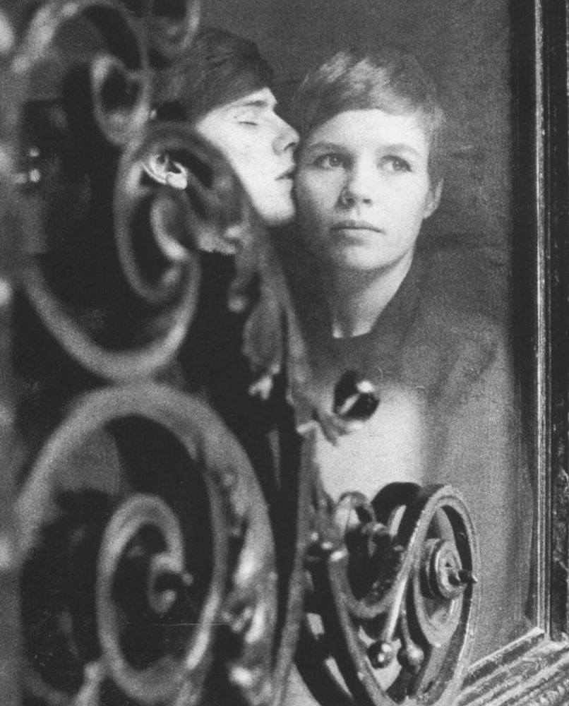 B&w portrait of Astrid Kirchherr and Stuart Sutcliffe behind a 19th Century iron door grille in Hamburg. 