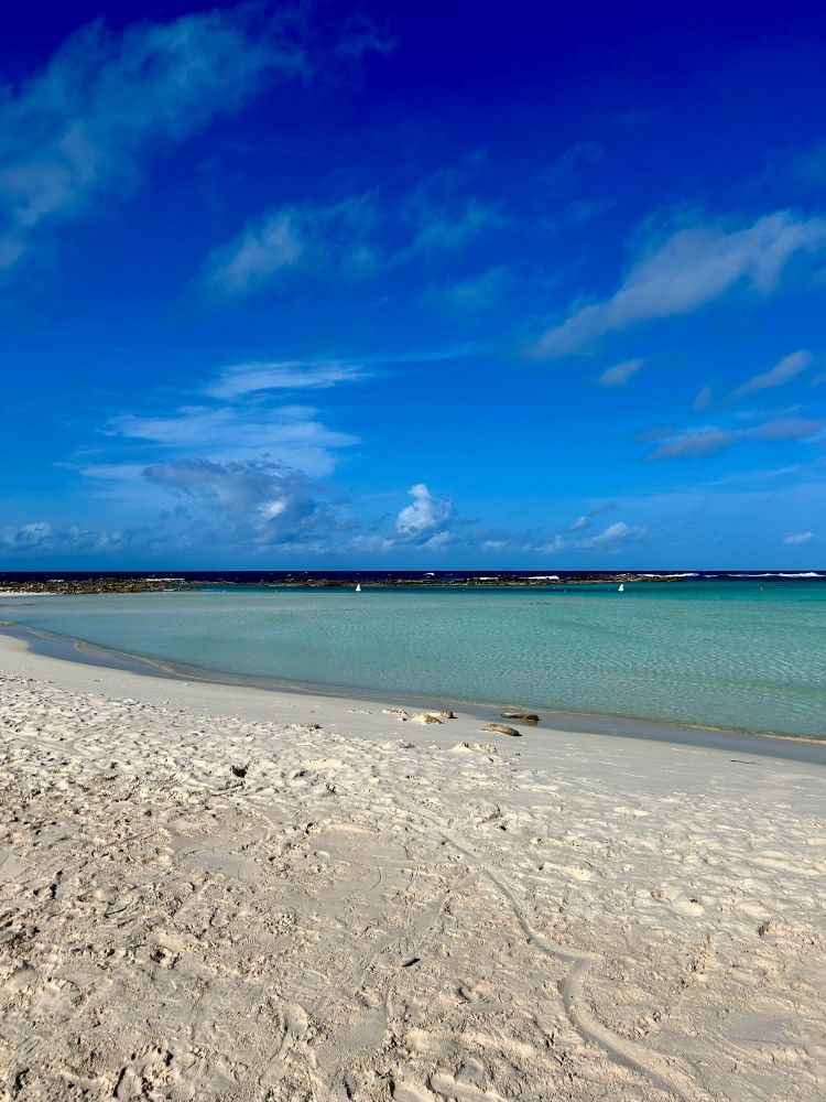 Brilliant blue sky above the Baby Beach Cove in Aruba. Soft white sand, aquamarine water. . 