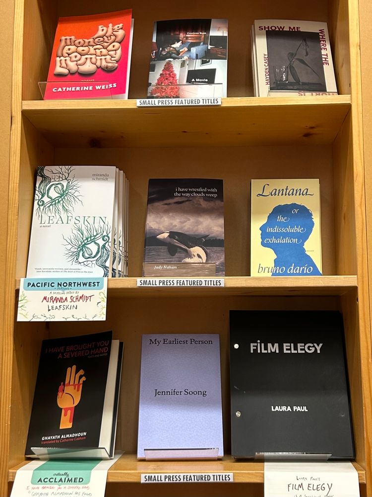 A section of the Small Press Featured Titles shelves at Powell’s bookstore, with 9 books shelved face-out