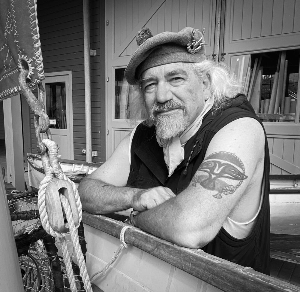Bearded old white man with a whale tail tattoo in a Seaforth Highlander bonnet, leaning on the rail of a peapod.