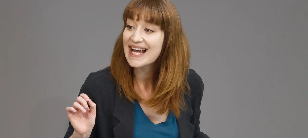 Heidi Reichinnek am Rednerpult. Sie ist eine jüngere Frau mit langen braunen Haaren und einem Pony. Sie trägt ein petrolfarbenes Oberteil, darüber einen dunklen Blazer. 