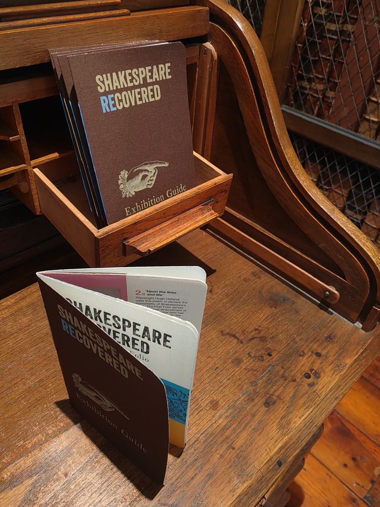 Colour photograph of exhibition guides on an antique wooden desk. The exhibition guides are titled 'Shakespeare Recovered'.