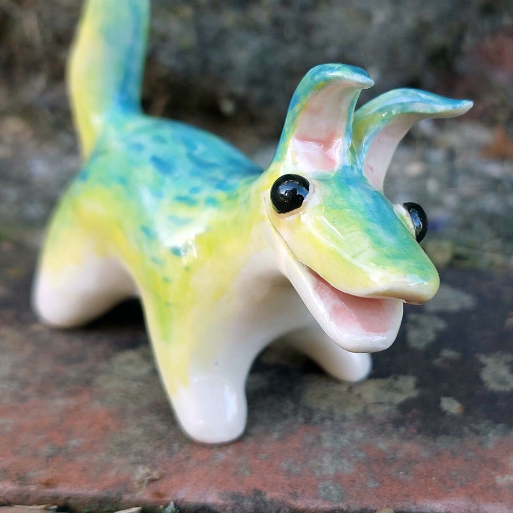 The same ceramic creature standing on some bricks in a 3/4 view. Its ear tips flop over slightly.