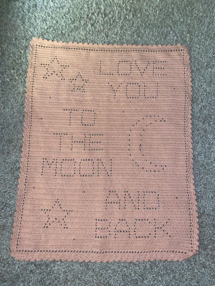 a dirty pink crocheted blanket where the words ”love you to the moon and back” can be seen together with three stars and a moon