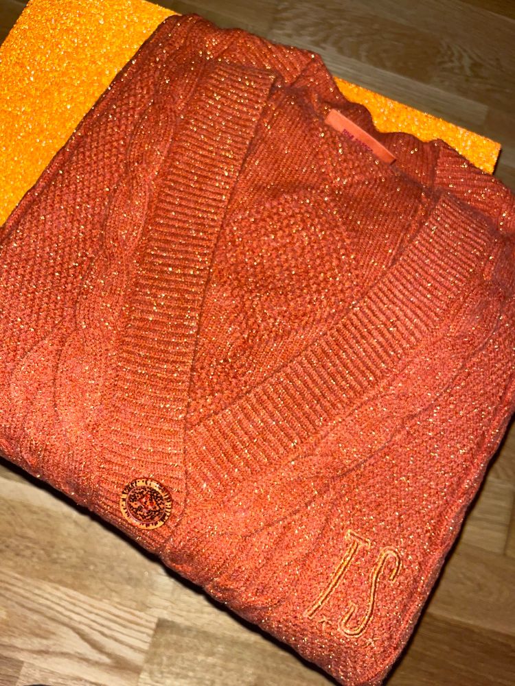 picture shows a folded up orange glittery cardigan
