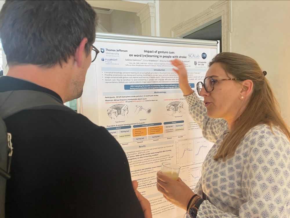 Dr. Kalénine is standing at her poster and speaking with a workshop attendee about the research.
