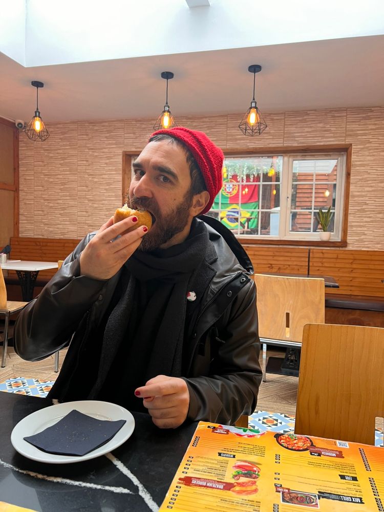 Me happily biting a coxinha de costela in a Brazilian restaurant in Birmingham. 