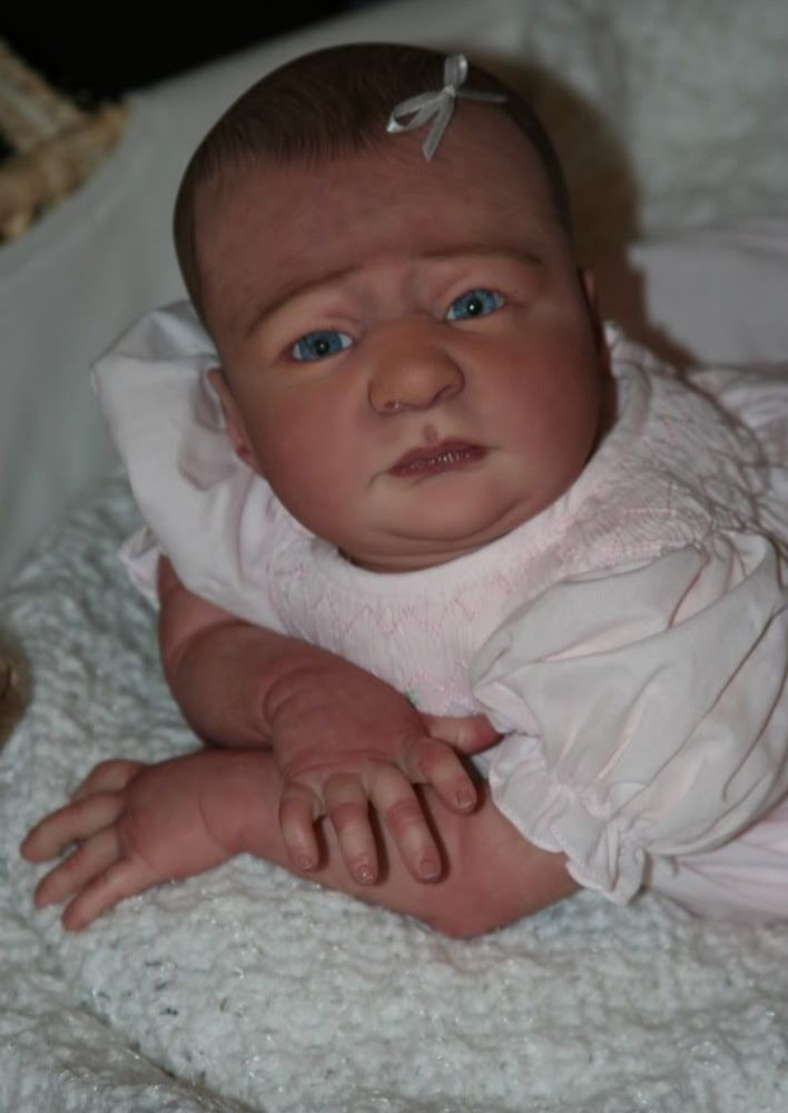 boneca do tipo bebê reborn estranhamente feia, com olhos azuis e uma expressão séria 