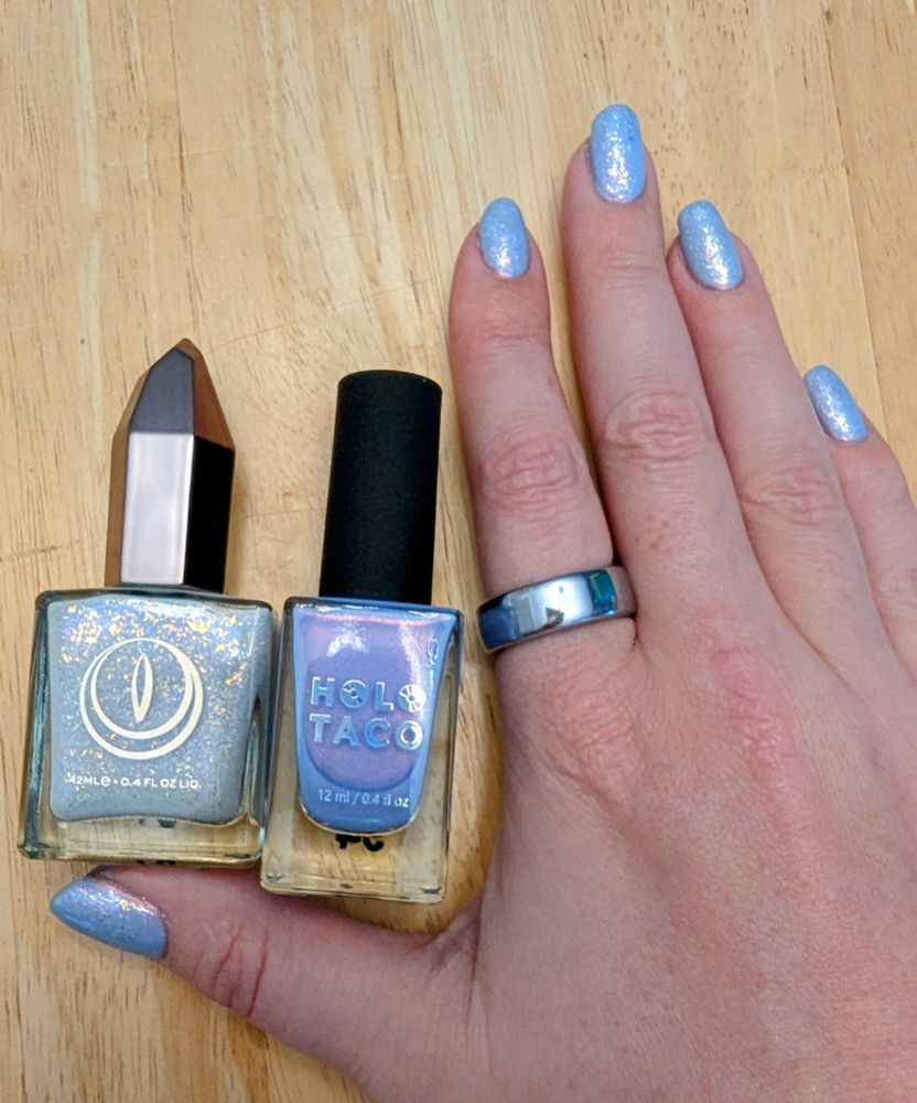 My right hand splayed on the kitchen table, showing off my icy blue manicure. Resting above my hand are two bottles of nail polish.