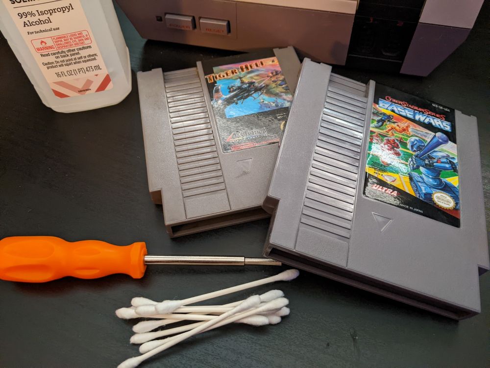 Two NES games Base Wars and Tiger-Heli
Q-tips
A bottle of isopropyl alcohol 
A gamebit screwdriver 