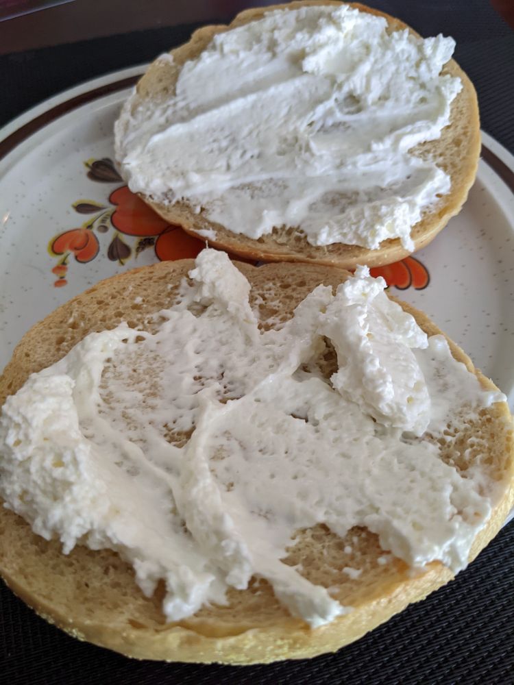 A bagel slices in half with cream cheese.